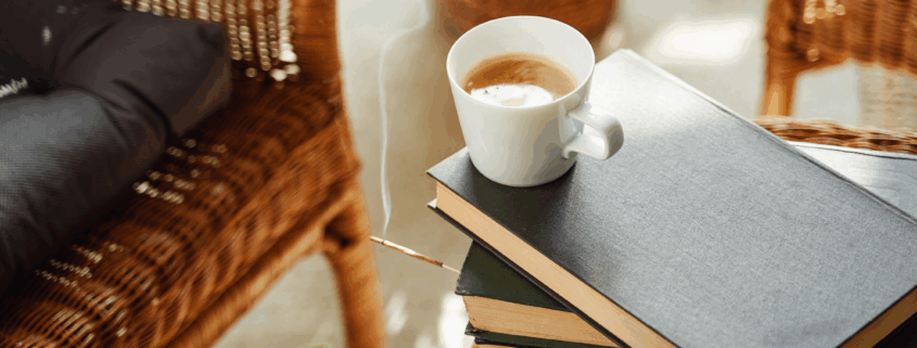 Lassú életmód pillanat – gőzölgő kávé könyvekkel egy fonott széken, a slow living hétköznapi örömeihez.